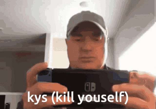 a man in a hat is holding a nintendo switch in his hands