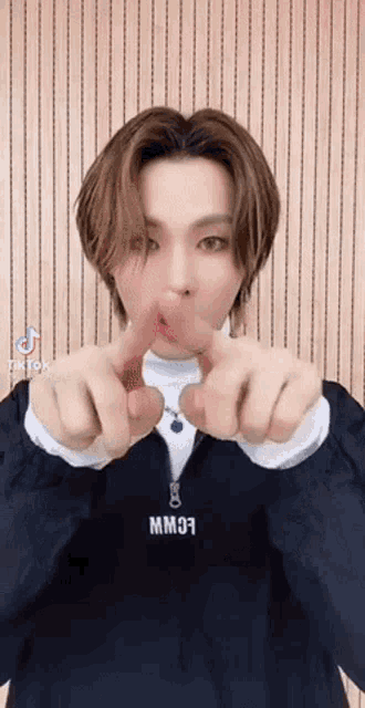 a man in a black jacket is making a heart shape with his fingers .
