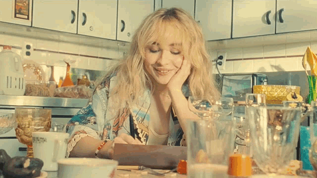 a woman sits in a kitchen with a clock that says 11:11