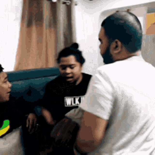 a group of people sitting on a couch talking to each other .
