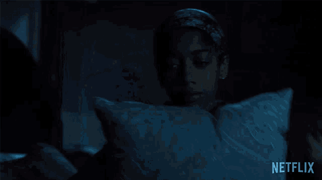 a woman covering her face with a pillow with netflix written on the bottom right