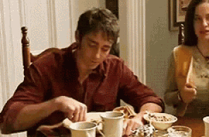 a man and woman are sitting at a table eating breakfast