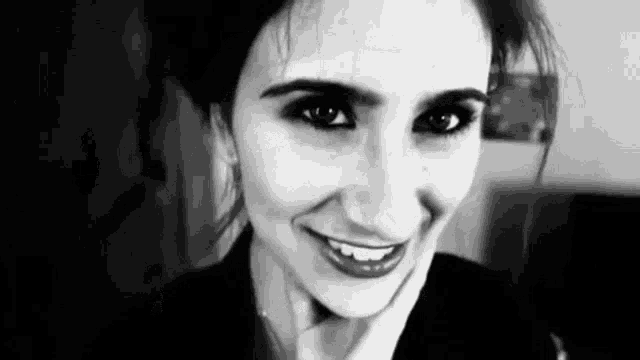 a woman is smiling in a black and white photo .