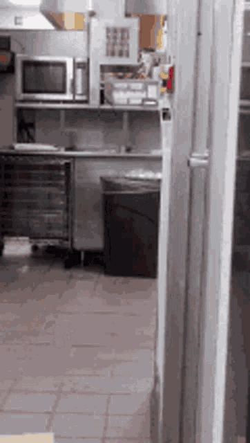 a kitchen with a microwave and a trashcan
