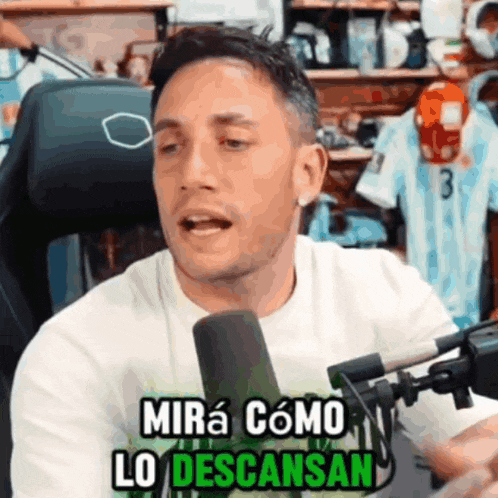 a man sitting in front of a microphone with the words mira como lo descansan on the bottom