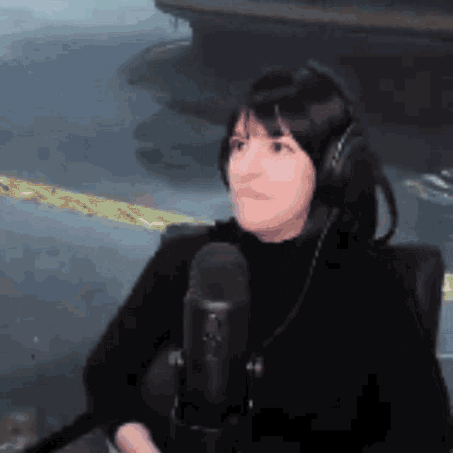 a woman wearing headphones and a microphone looks at the camera