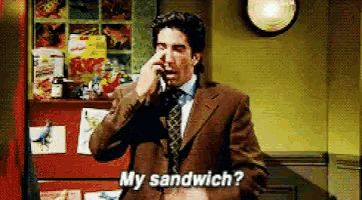 a man in a suit is talking on a cell phone and says my sandwich ?
