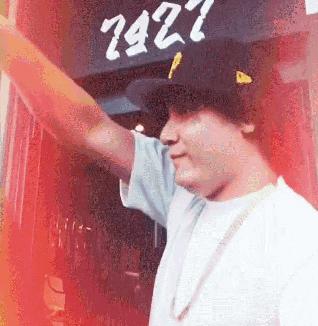 a man wearing a hat and a white shirt stands in front of a sign that says 2927