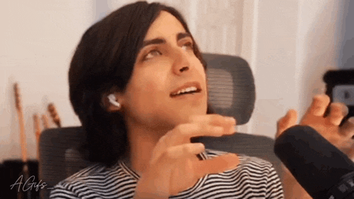 a man in a striped shirt is sitting in front of a microphone and making a funny face
