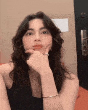a woman with a ring on her finger looks at the camera with her hand on her chin