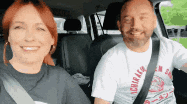 a man and woman are sitting in a car and the man is wearing a shirt that says chiraku