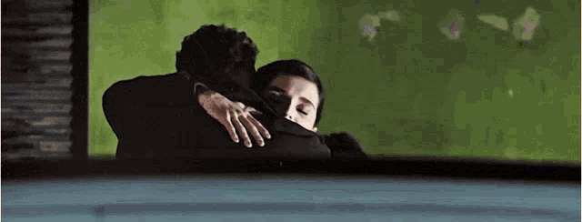 a man and a woman are hugging each other in a dark room .