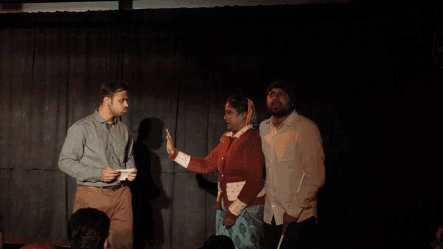 a group of people are standing on a stage and one of them is holding a piece of paper in his hand