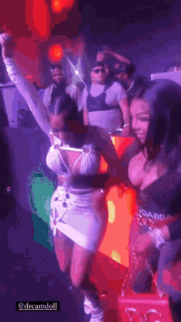 a group of women are dancing in a club with a man in the background .