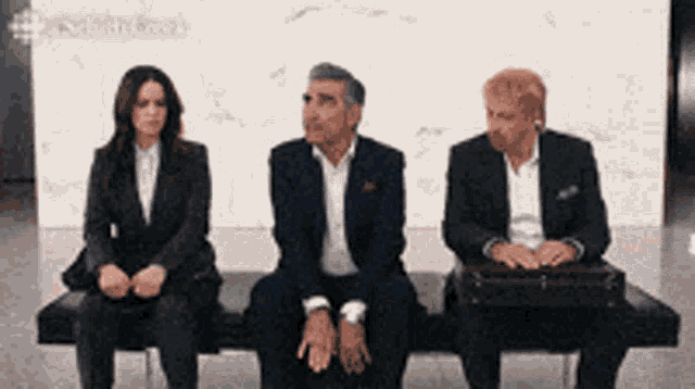 three people in suits are sitting on a bench
