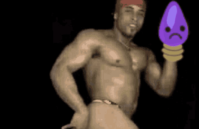 a shirtless man is standing in front of a purple object with a sad face on it .