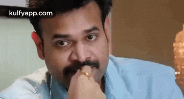a man with a mustache and a ring on his finger is eating something .