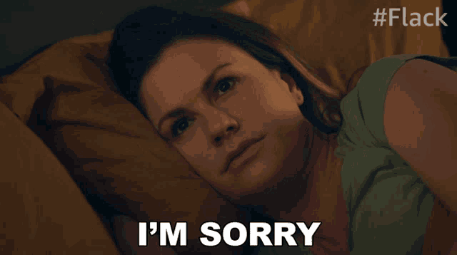 a woman is laying in bed with the words i 'm sorry written on her face