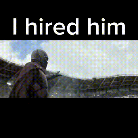 a man in a superhero costume is standing in front of a stadium with the words `` i hired him '' .