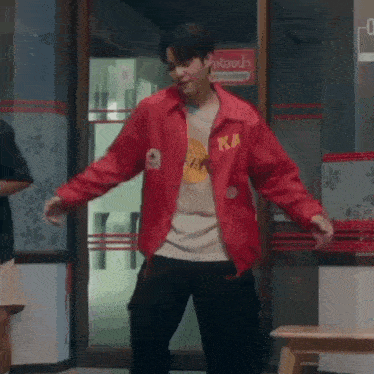 a man wearing a red jacket and black pants is dancing in a room .