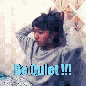 a girl is sitting on a bed with her hands on her head and the words be quiet written in blue