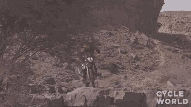 a person riding a motorcycle on a rocky path with the words cycle world below them