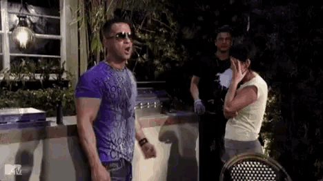 a man in a purple shirt and sunglasses is standing next to a woman in a yellow shirt .