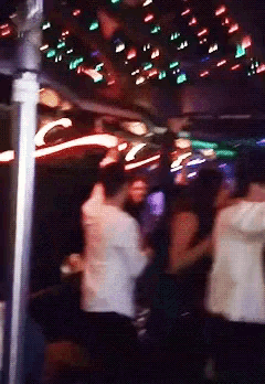 a blurry photo of people dancing in a club with a sign that says ' coca cola ' on it