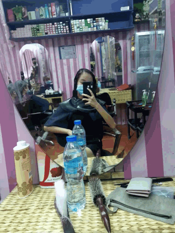 a woman taking a picture of herself in a mirror with a bottle of water