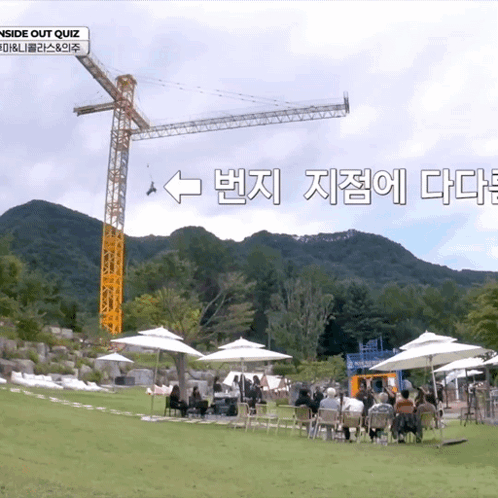 a group of people sitting under umbrellas in front of a crane that says outside out quiz
