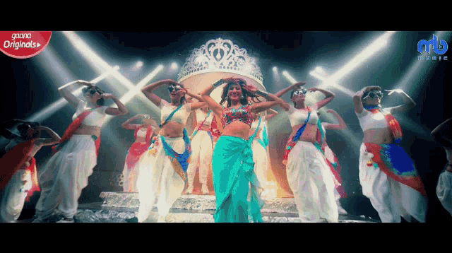 a group of women are dancing in front of a large crown that says originals on it