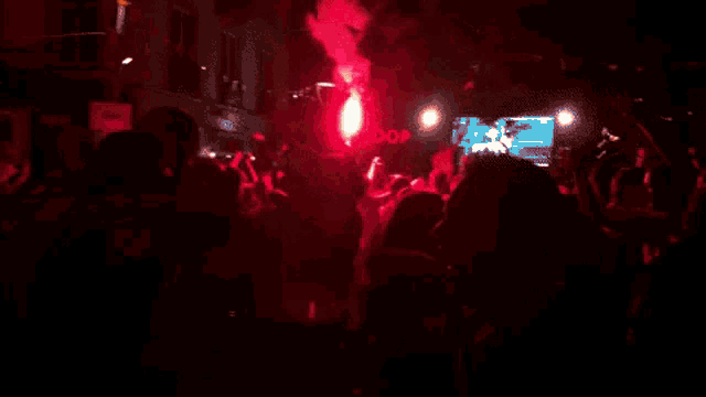 a group of people are dancing in a dark room with red lights .