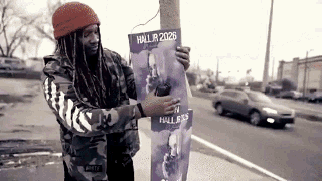 a man is holding a poster that says hall jr 2026