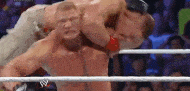 two men are wrestling in a ring and one of them is holding the other 's neck .