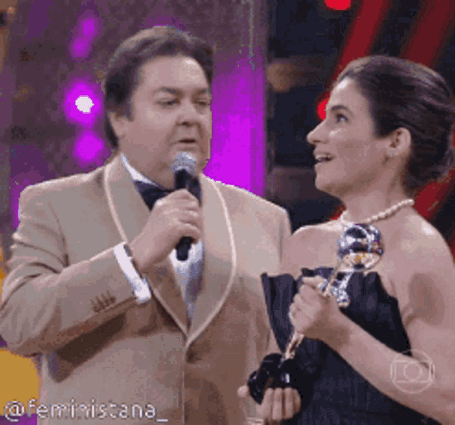 a man speaking into a microphone next to a woman