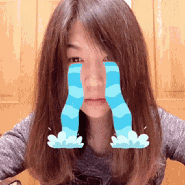 a woman with tears coming out of her eyes is wearing a gray shirt