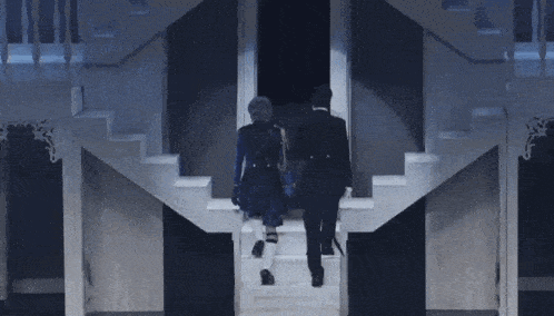 two people are walking down stairs in a dark room .