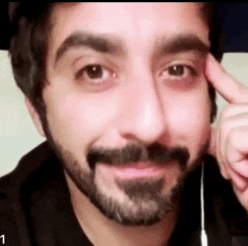 a man with a beard and mustache is making a funny face with his hand on his forehead .