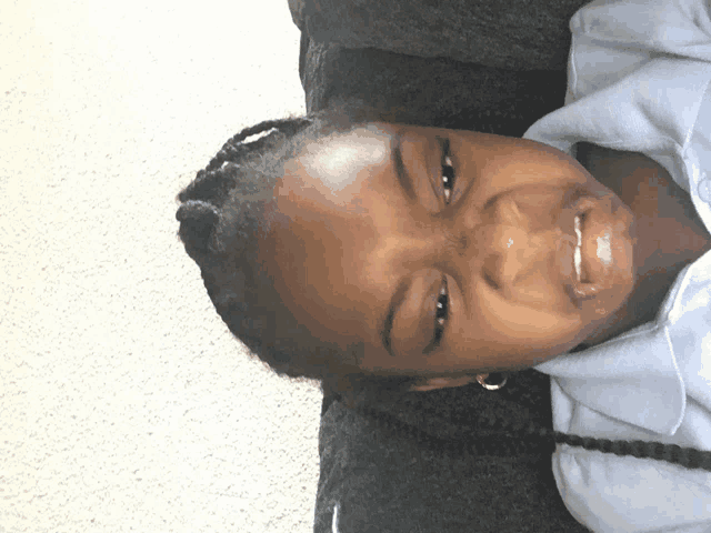 a little girl with braids is smiling and looking down