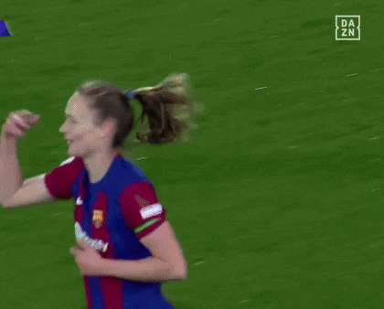 two soccer players are giving each other a high five on the field .
