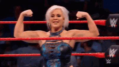 a female wrestler is flexing her muscles in a wrestling ring .
