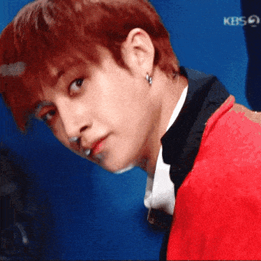 a close up of a man 's face with red hair and earrings
