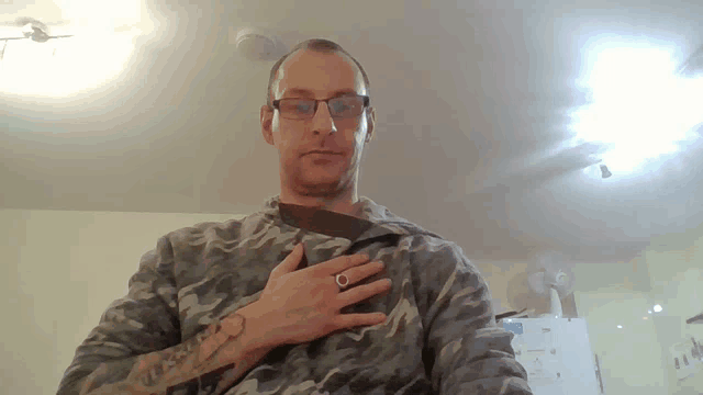 a man wearing glasses and a ring on his finger