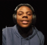 a man wearing headphones and a blue hoodie is smiling