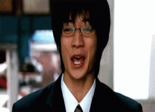 a man in a suit and tie is making a funny face with his mouth open .