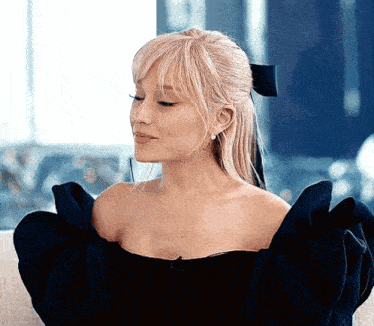 ariana grande is wearing a black off the shoulder dress with ruffled sleeves .