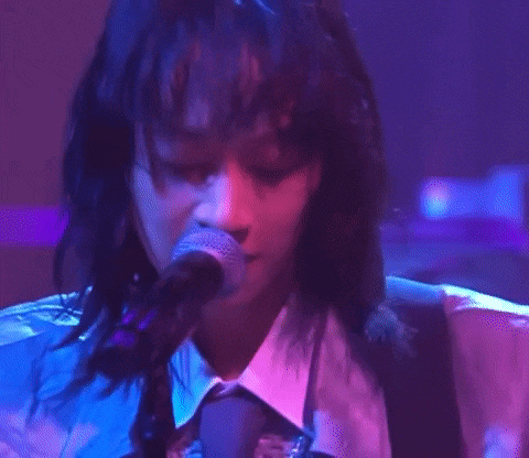 a close up of a person singing into a microphone on a stage .
