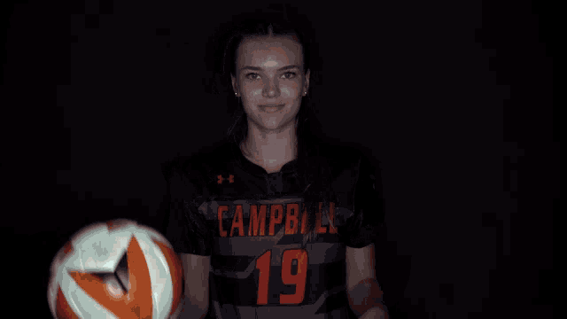 a girl wearing a campbell jersey is holding a soccer ball