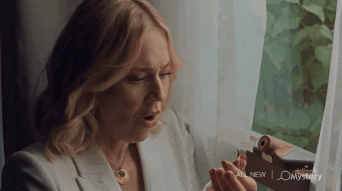 a woman in a white jacket is holding a card that says all new mystery