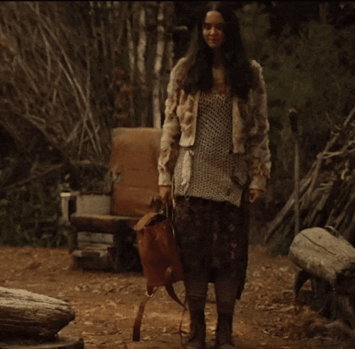 a woman in a fur coat is holding a backpack